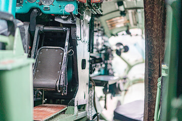 Military cockpit interior mix of green and black tones, large steering wheel, array of dials and...