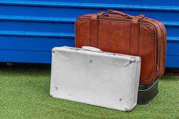 Vintage suitcase and weathered wooden crate on artificial grass or textured fabric surface, outdoor...