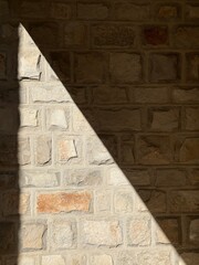 Triangular shadow on a stone wall.