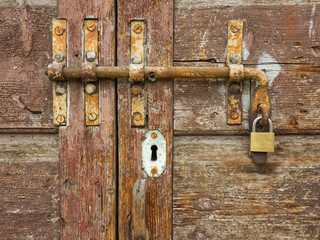 Old wooden door. Old wooden background mit bolt. Rusty iron bolt. Patina metal surface. Vintage latch and lock. Aged wooden plank. Secured bolt mechanism. Vintage  mechanism. Vintage aesthetic. Secure