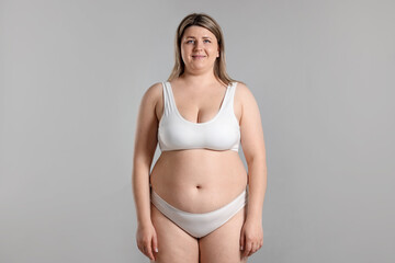 Fototapeta premium Weight loss. Plus size woman in underwear on gray background