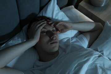 Frustrated man suffering from insomnia in bed indoors, above view