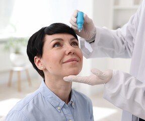 Ophthalmologist applying medical drops onto patient's eye in clinic, closeup