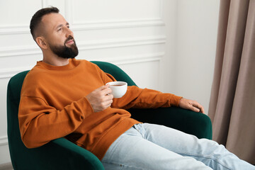 Obraz premium Harmony. Man with tea in armchair at home