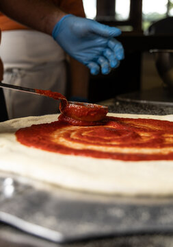 Using a Ladel to Put Marinara Sauce on a Pizza