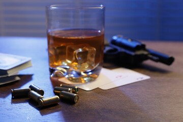 Mafia and criminal world. Bullets, gun, whiskey, money and playing cards on wooden table indoors, closeup