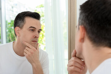 Handsome man after shaving near mirror at home