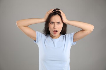 Portrait of shocked woman on grey background