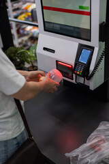 A woman scans items at a self-checkout. 