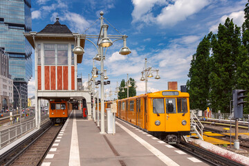 Yellow U-Bahn trains at elevated station platform in Berlin Germany with historic control tower