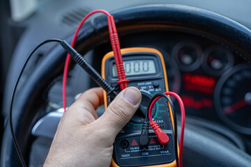 Car diagnostics.A multimeter for checking the battery power supply in the car.An auto electrician.
