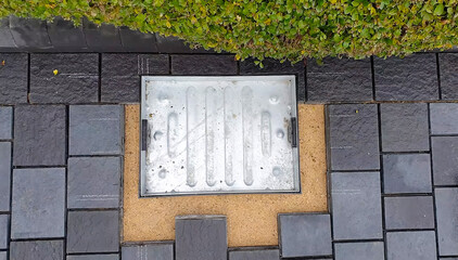 Drain cover installed in a landscaped pathway with modern paving stones