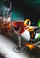 Cocktail drink garnished with an orange twist on a marble countertop in a cozy setting at night