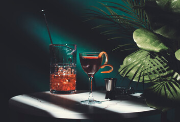 Cocktail on a marble table with tropical plants in dimly lit bar setting at night