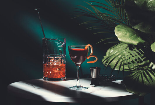 Cocktail on a marble table with tropical plants in dimly lit bar setting at night