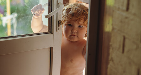 Child Standing at an Open Door During a Warm Afternoon in a Backyard Garden
