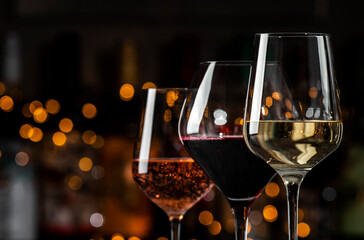 An array of wine glasses showcases red, rose, and white wines, illuminated by warm bokeh lights, creating a festive atmosphere.
