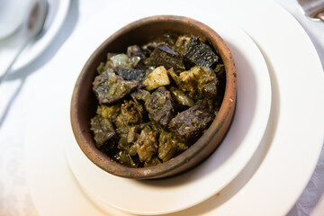 Caucasian cuisine, fried chicken liver with onions and pepper in a ceramic plate in cafe