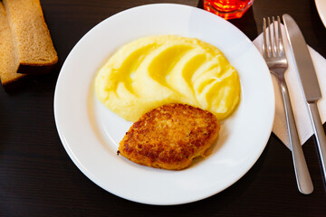 Roast meat cutlet with mashed potatoes served in a white ceramic plate in a restaurant