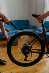 Two people cleaning bicycle wheel with steam cleaner, removing dirt and grime in cozy home...