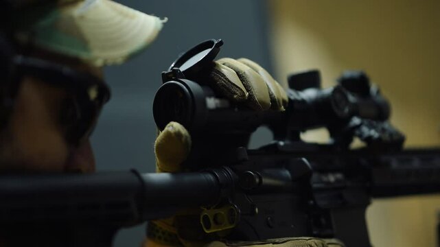 Person practices shooting skills at indoor range with tactical rifle