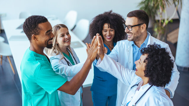 Group of Physicians Celebrating Teamwork With High Fives in a Modern Office - Powered by Adobe