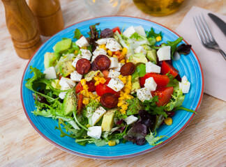 Spanish typical cuisine, salad with roasted sausages, tomato, avocado and corn in a cafe
