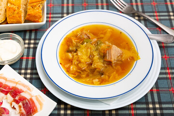 Thick Russian-style cabbage soup (Shchi) with pork cooked in mushroom broth served with sour cream..