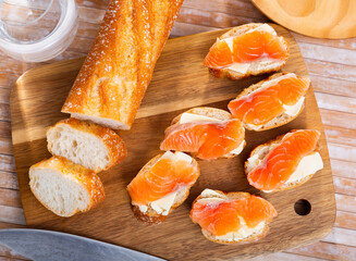Sandwiches with butter and salted salmon on wooden board. Tasty seafood appetizer