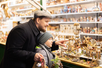 Father and son choose small statuettes for a Christmas composition. Visitors to the holiday fair...