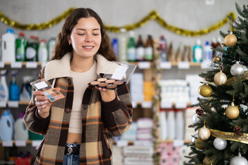 In Christmas decorated shop, woman examines product and doubts, chooses eye shadow pallet, study...