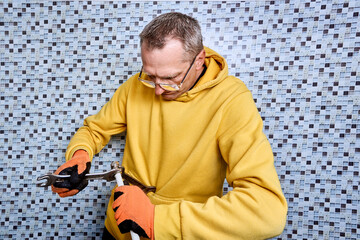Plumber uses two open end wrenches to tighten securing nut of compression fitting onto end of...