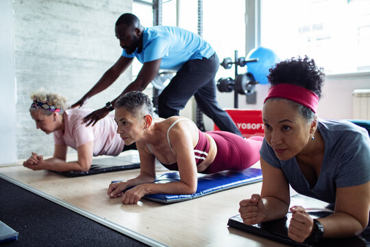 Senior women doing workout with personal trainer in gym