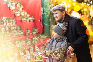 During Christmas fair, father and son choose composition, bouquet of fir branches, eucalyptus...