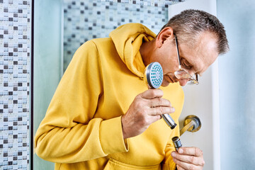 Attaching handheld showerhead to flexible hose, plumber connects threaded fitting by rotating head...