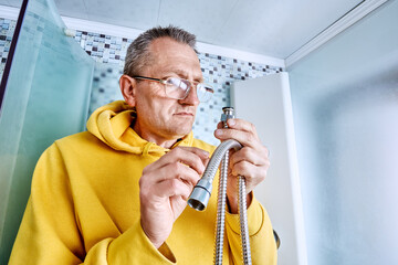 Plumber inside shower cabin examines rubber gasket of shower hose connector before replacing...