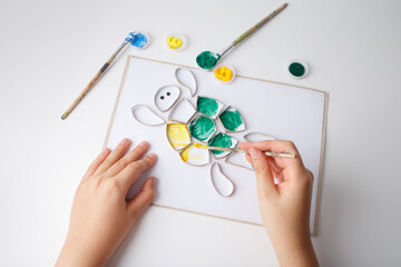 Handmade turtle craft made from painted cardboard pieces on white paper. DIY art project for kids...