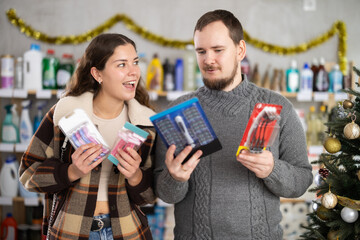 Happy couple choosing razors in supermarket before celebrating Christmas