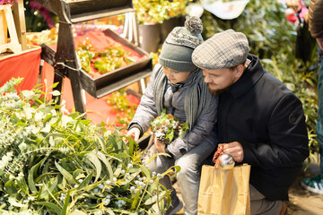 Father and son choose flowers, plants and branches for a winter flower arrangement and home...