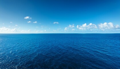 Obraz premium vast expanse of blue ocean water on a sunny day with clear horizon and white clouds in sky