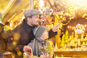 Dad enthusiastically shows his son beautiful decorations at the Christmas Market. Man and his son...