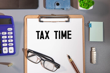 Closeup of Tax Time written on yellow paper note with paperclip