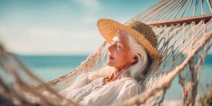 A serene older woman with elegant white hair and a straw hat peacefully rests in a hammock, eyes closed, enjoying the warm sun and gentle breeze by the ocean, embodying tranquil retirement bliss