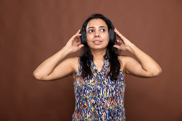 Pretty woman with peaceful expression, looking upward and enjoying his favorite songs. Female model...