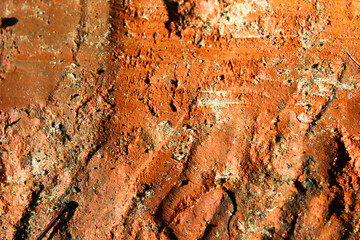 close-up of reddish clay soil with a rough uneven surface and grooves. abstract texture background with copy space