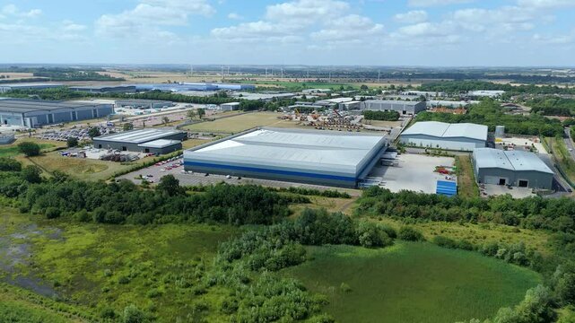 Aerial drone of large industrial warehouse distribution centers and Data Centers with wind turbines renewable energy and business in Biggleswade England UK