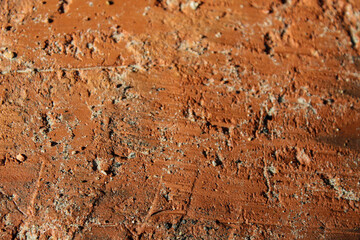 close-up of reddish clay soil with a rough uneven surface. abstract texture background with copy space