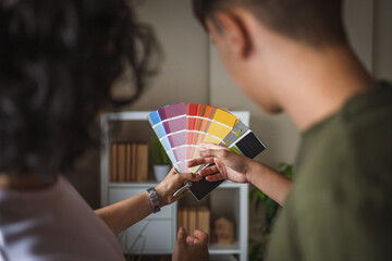 Close up on hands of man and woman holding color swatches at home