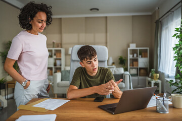 Obraz premium teenage boy talk on video call while his mom stand next to him