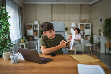 teenage boy talk on video call while his mom sit in the background